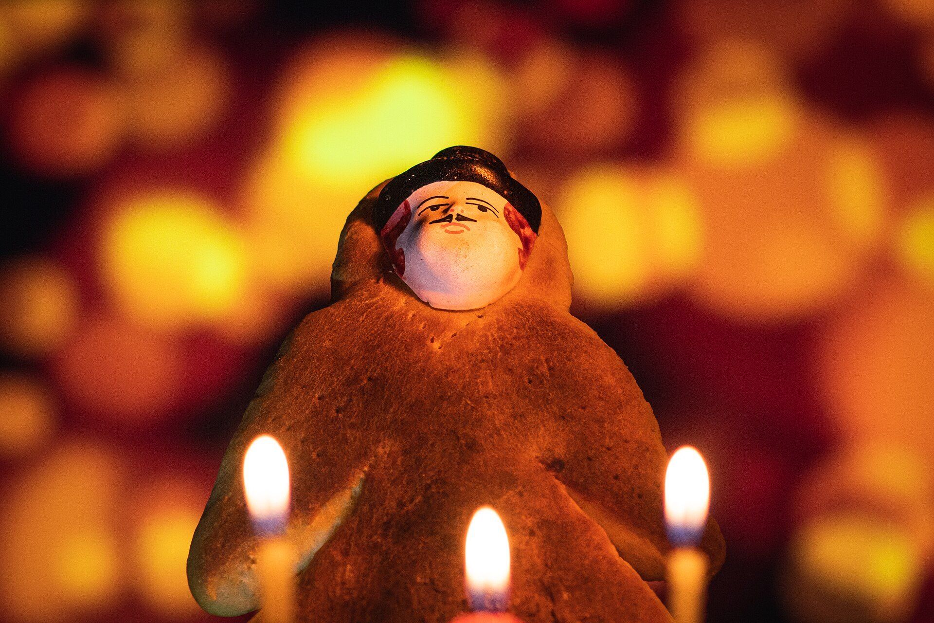 Una guagua de pan: un pan con forma de bebé envuelto, con una carita pintada, iluminado por velas encendidas.